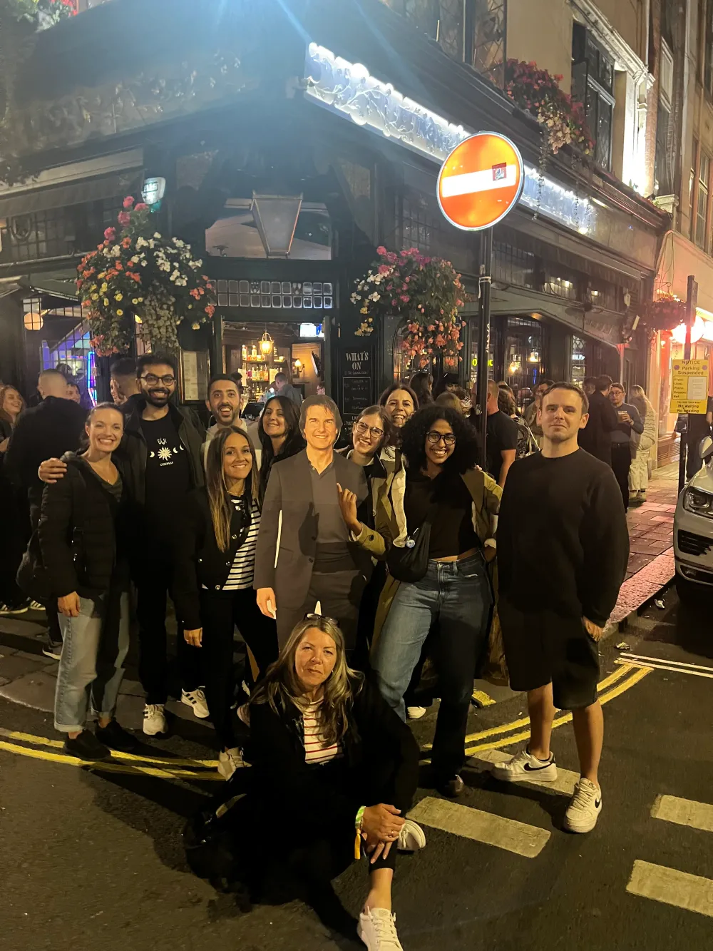 Jimmy Dushku with a large group of friends and a cardboard cutout of Tom Cruise outside a pub at night