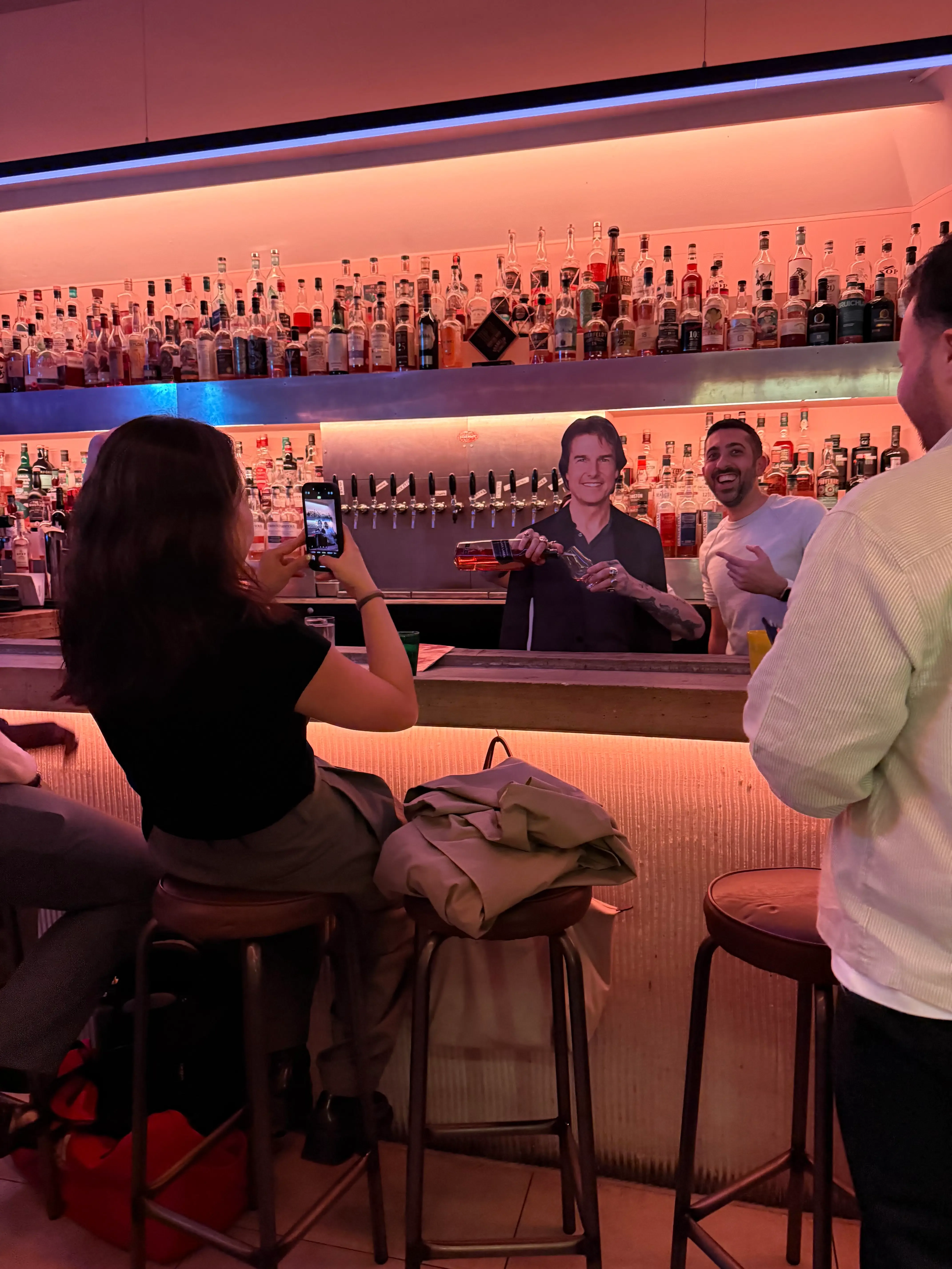 A cardboard cutout of Tom Cruise posed behind a bar pouring a drink