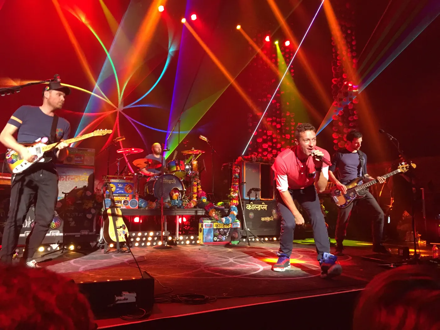 Chris Martin singing on stage at the Belasco Theatre with red stage lighting
