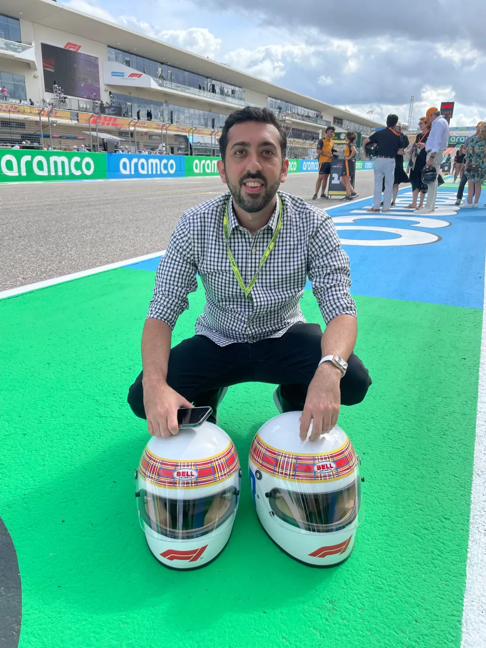 Jimmy Dushku kneeling beside two Bell helmets in the tartan Race Against Dementia livery