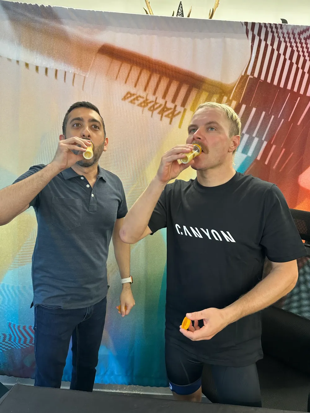 Jimmy Dushku and Valtteri Bottas drinking ginger shots