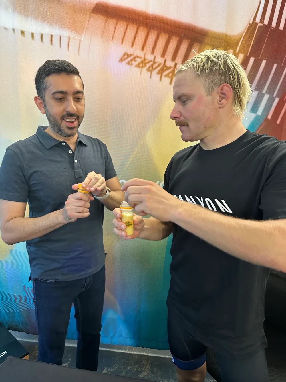 Jimmy Dushku and Valtteri Bottas opening ginger shot bottles from JuiceLand