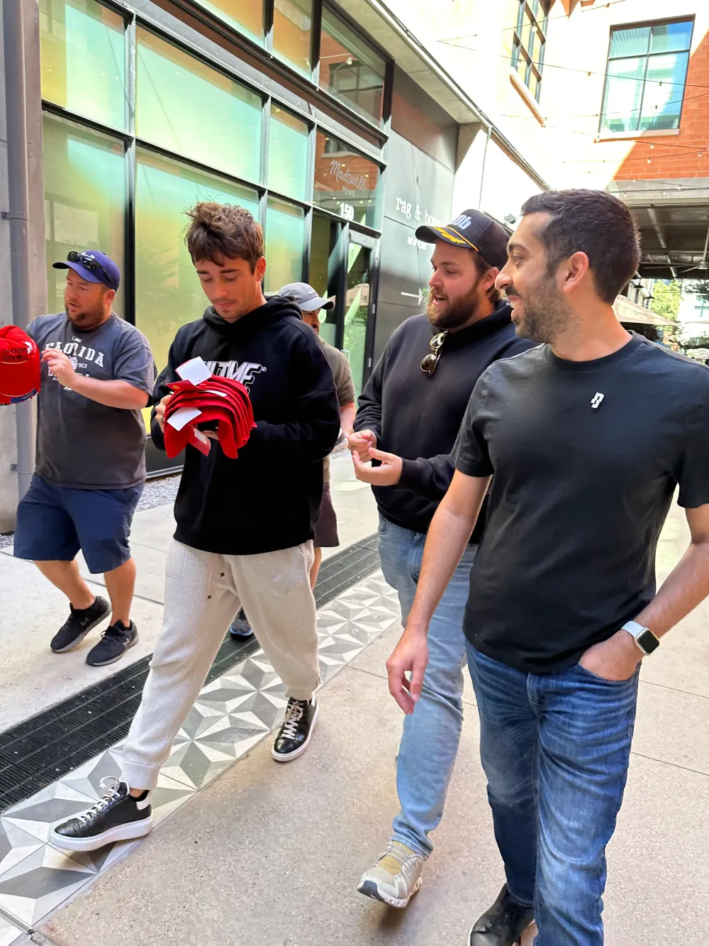 Jimmy Dushku walking alongside Charles Leclerc as he signs items for fans